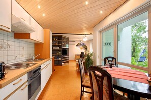 A modern kitchen with a dining area, wooden ceiling, and a view of the outdoors. - Apartment 'Stumpp´s Appartement' with Private Terrace, Wi-Fi and Air Conditioning (Heroldstatt)