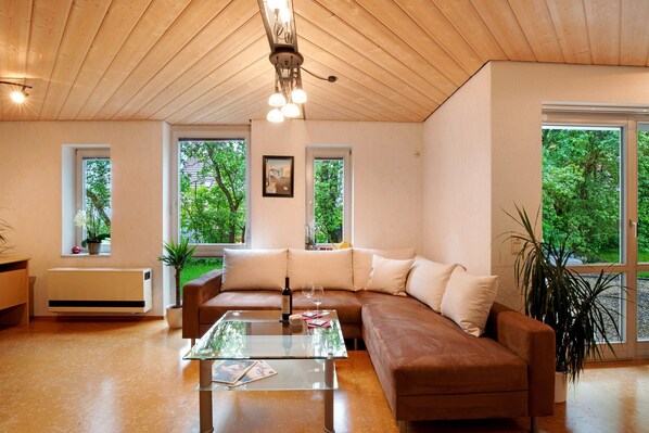 A modern living room with a brown leather sofa, a glass coffee table, and a ceiling light fixture.