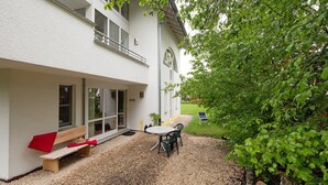 A building with a patio area, a bench, a table with chairs, and a small garden with a statue. - Apartment 'Stumpp´s Appartement' with Private Terrace, Wi-Fi and Air Conditioning (Heroldstatt)