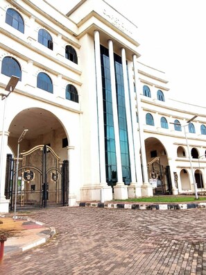 A large building with a central entrance, multiple windows, and a paved courtyard. - Best of Shimawa 2-Bed Luxury, 24/7 Electric/Wifi (Shimawa)