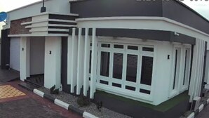 Un edificio moderno con facciata curva, ampie finestre e un piccolo ingresso con gradini.