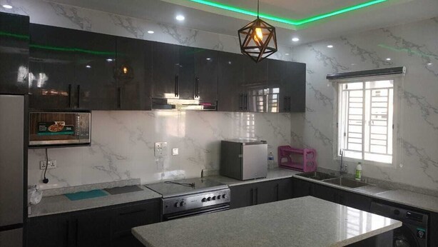 Una cucina moderna con un piano di lavoro in marmo, elettrodomestici in acciaio inossidabile e un'originale lampada a sospensione geometrica.