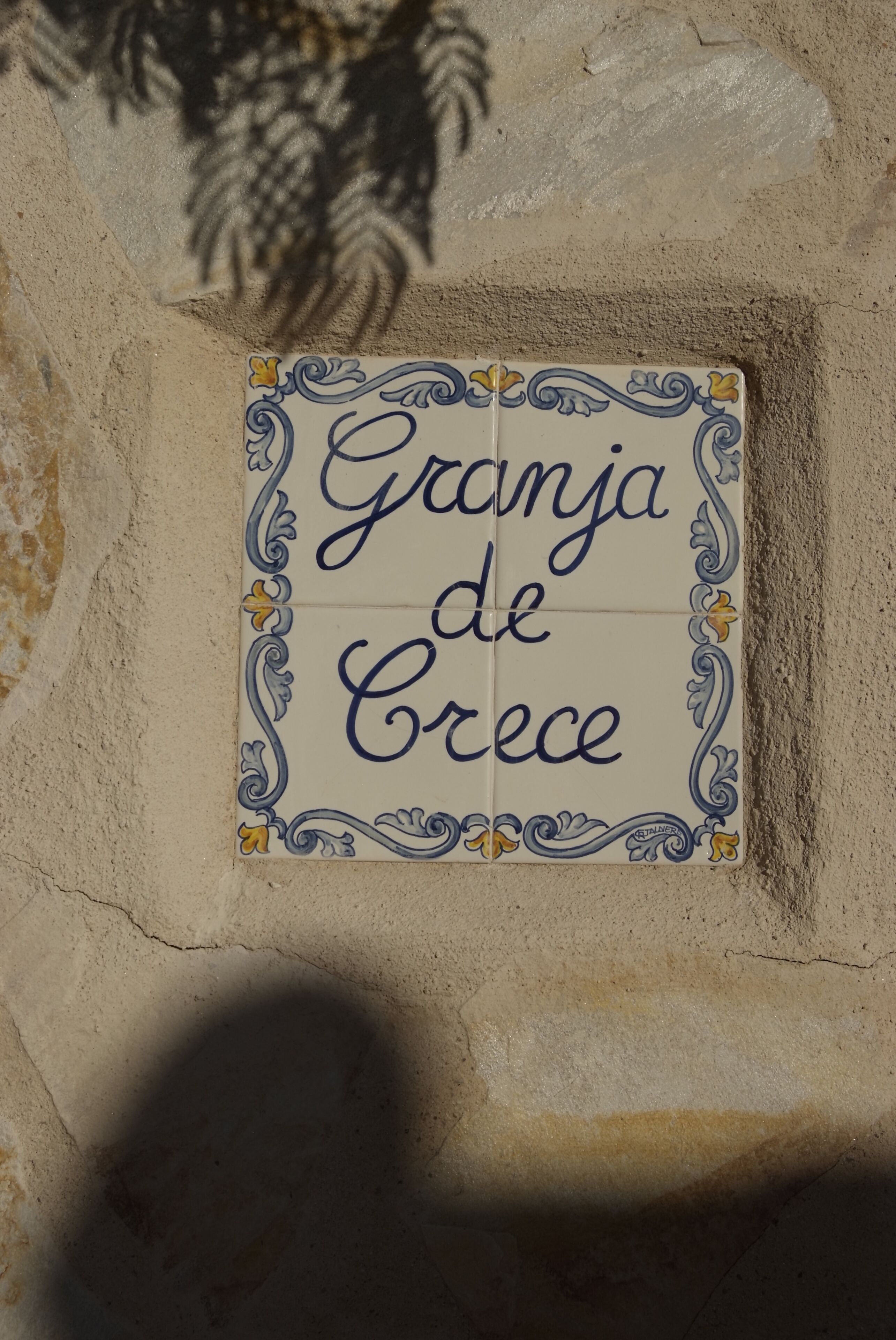 Eine Fliese mit der Aufschrift 'Granja de Crece', die an einer Steinwand angebracht ist.