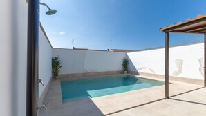 A swimming pool with a pergola and potted plants.