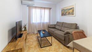 A living room with a flat-screen TV, a sofa, a coffee table, and a painting on the wall.