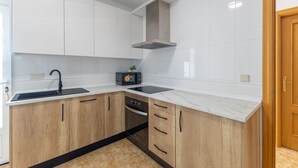 A modern kitchen with white cabinets, a black sink, and a built-in oven.