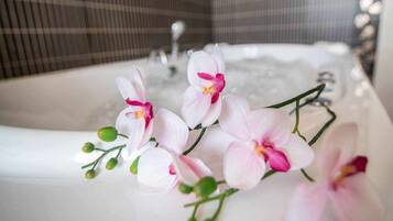 Eine Badewanne mit Wasser, umgeben von rosafarbenen Orchideen.