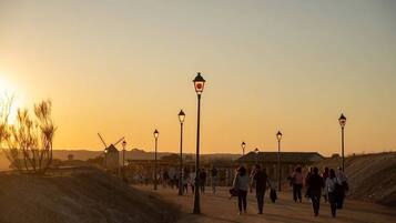 A sunset scene with people walking on a path, street lamps, and windmills in the background.