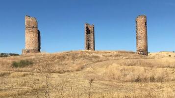 Three stone pillars on a grassy hill under a clear sky.
