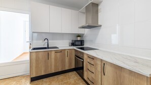 A modern kitchen with white cabinets, a black countertop, and a built-in oven. - Callejón del Pozo V, accommodation Puy du Fou (Galvez)