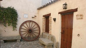 A cobblestone courtyard with a large wooden wheel, stone steps, and wooden doors. - Callejón del Pozo V, accommodation Puy du Fou (Galvez)