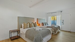 A bedroom with two beds, a nightstand, and a sliding door leading to a balcony. - Lake Metung | Modern Lake House Escape (Metung)