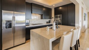 Una cocina moderna con una isla central, electrodomésticos de acero inoxidable y un dispensador de agua.