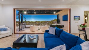 Una sala de estar moderna con un sofá azul, una mesa de centro y vistas a un balcón con mobiliario exterior.