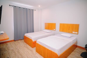 Une chambre avec deux lits, des têtes de lit en bois, un bureau et un rideau.