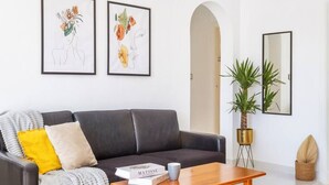 Een moderne woonkamer met een donker leren bank, een houten salontafel en twee ingelijste bloemwerken aan de wand.