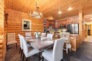 L’intérieur d’une cabane en rondins comprend un coin repas, une cuisine et un lustre.