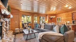 A log cabin interior with a living room, dining area, and kitchen.