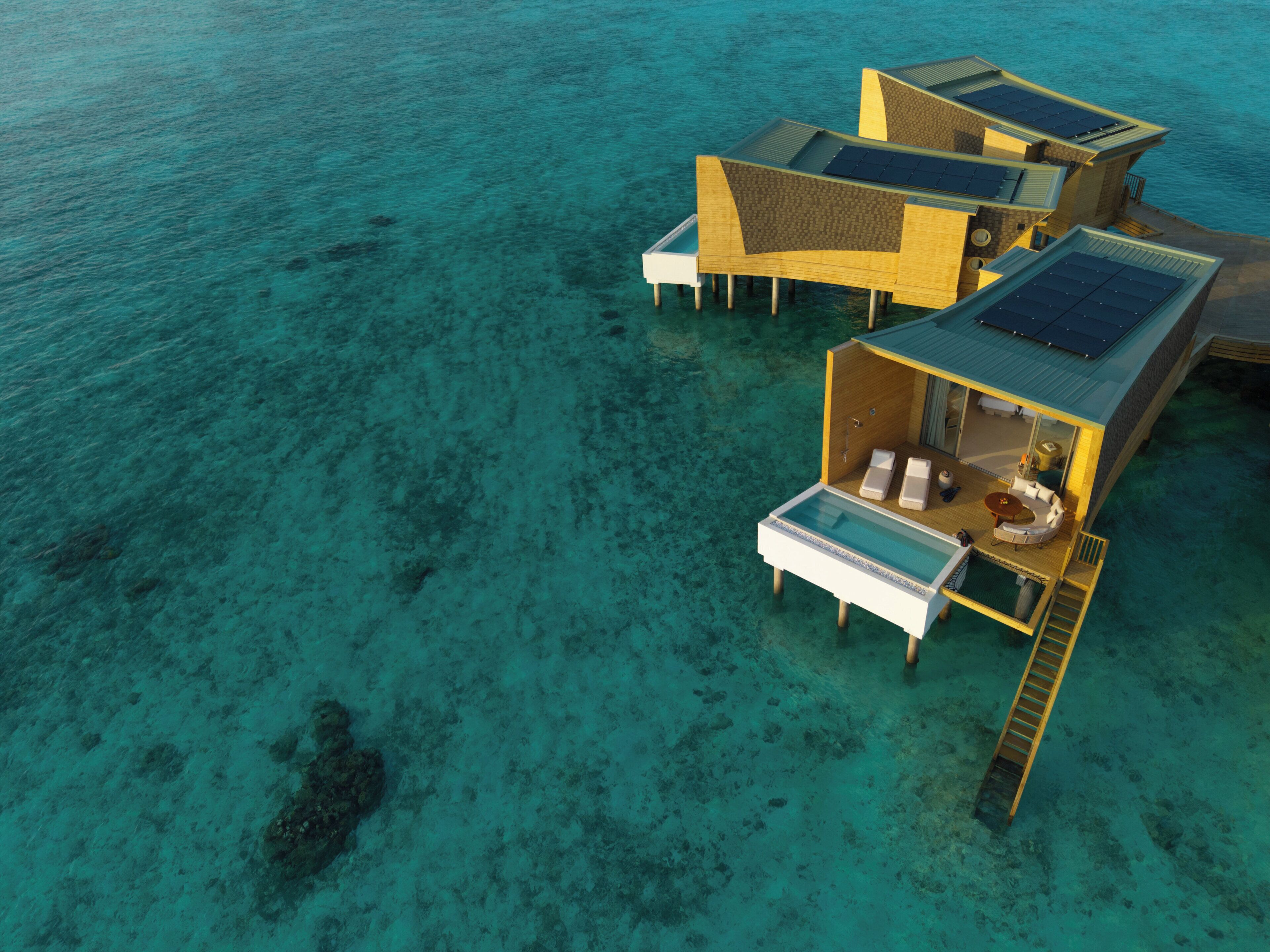 Una cabaña sobre el agua con piscina privada, paneles solares y una terraza de madera.