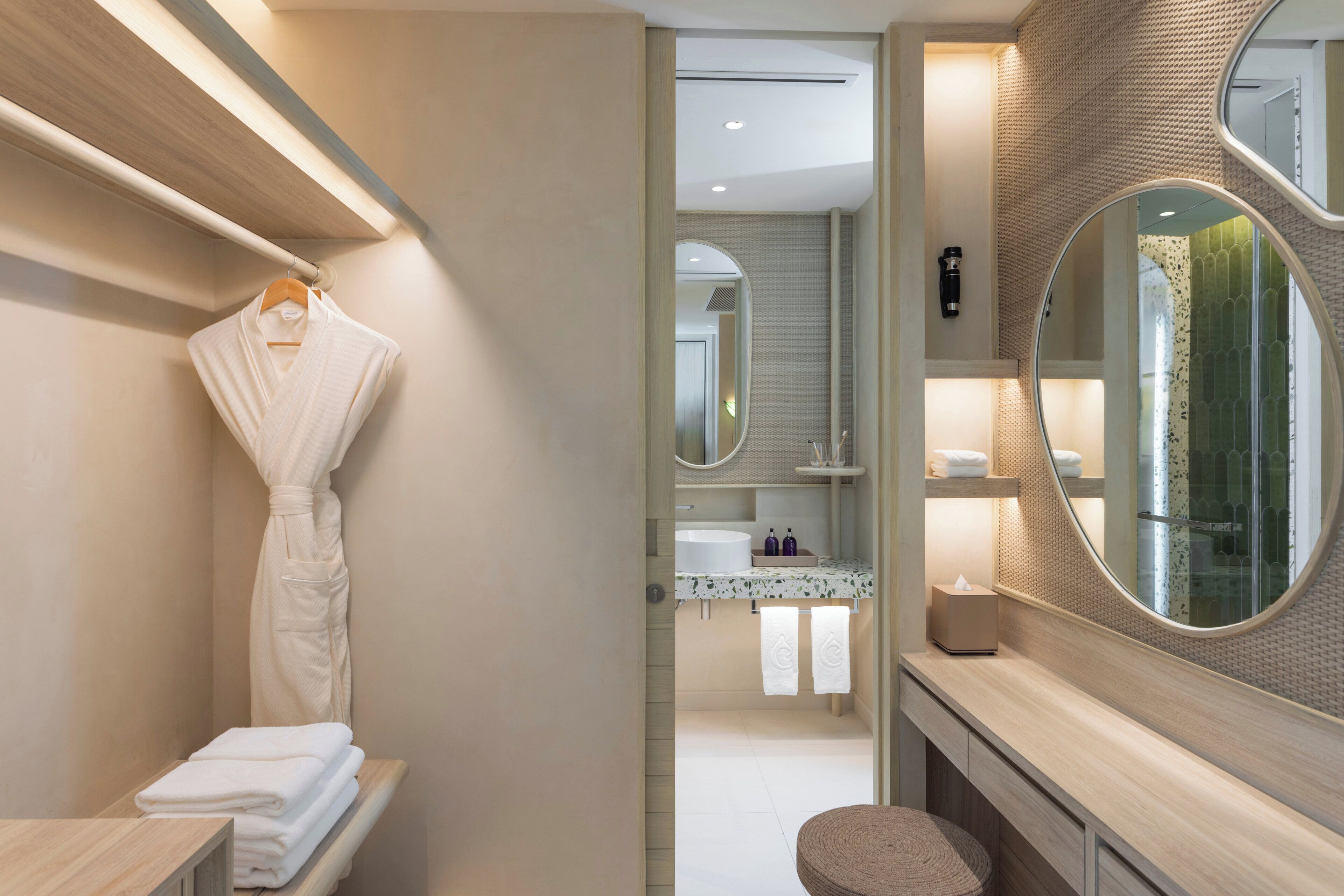 A modern bathroom with a wooden vanity, a round mirror, and a towel rack.