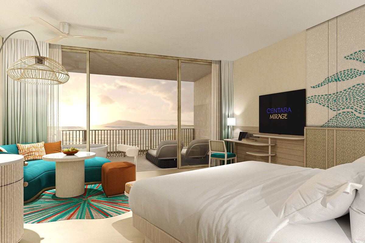 Una camera d'albergo moderna con un letto grande, una TV, un balcone vista mare e un'area salotto con vista sull'oceano.