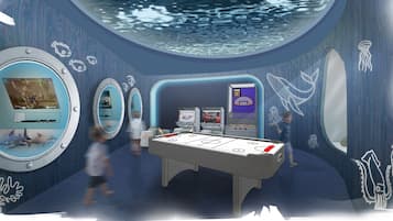 An indoor recreational area with a pool table, arcade machines, and a large screen.