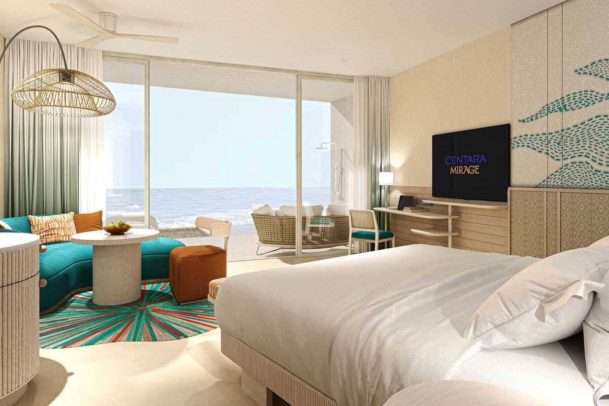 Una moderna camera d'hotel con un ampio letto, una televisione, un'area pranzo e vista sull'oceano.