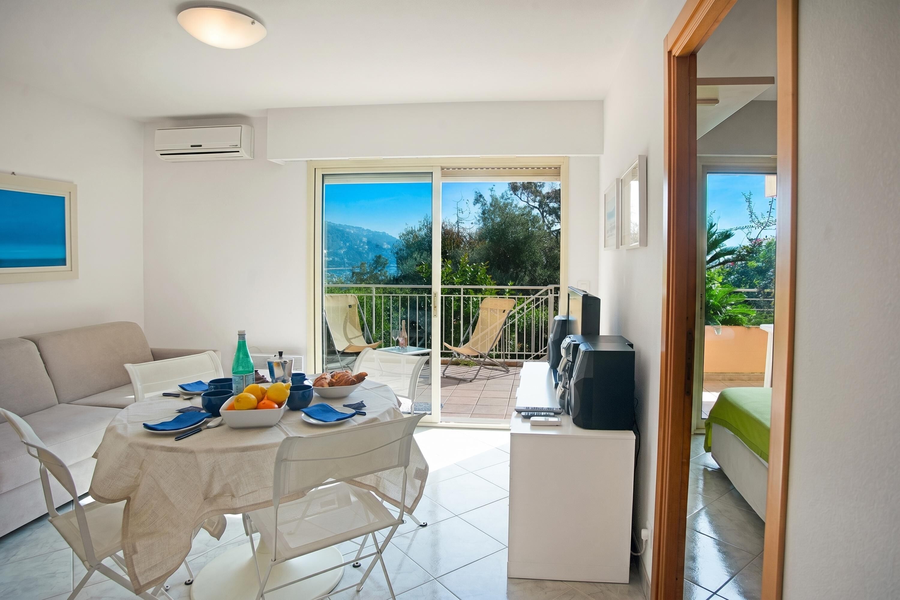A modern living room with a dining table, sofa, and a view of the outdoors.