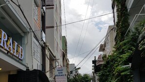 A narrow street with a hotel named "NHAT KIM HOANG 2" on the left, a "RALPH" store on the right, and motorcycles parked along the sides.