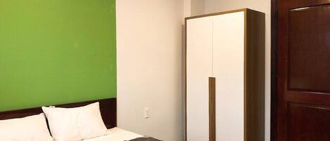 A hotel room with a bed, a wardrobe, and a door.