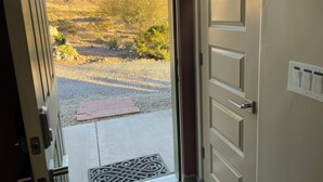 Une porte ouverte donnant sur un patio d’où l’on peut admirer un paysage montagneux.