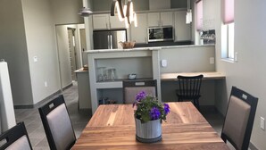 Une cuisine moderne dotée d’un îlot central, d’une table à manger avec des chaises et d’un éclairage suspendu.