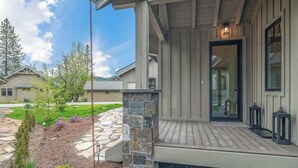 A residential building with a stone pillar, a wooden deck, and a door with a light fixture.