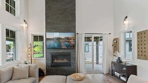 A spacious living room with a fireplace, large windows, and a view of a body of water.