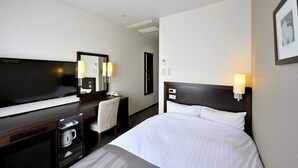 Una habitación de hotel con una cama, un escritorio, una silla, un televisor y un espejo.