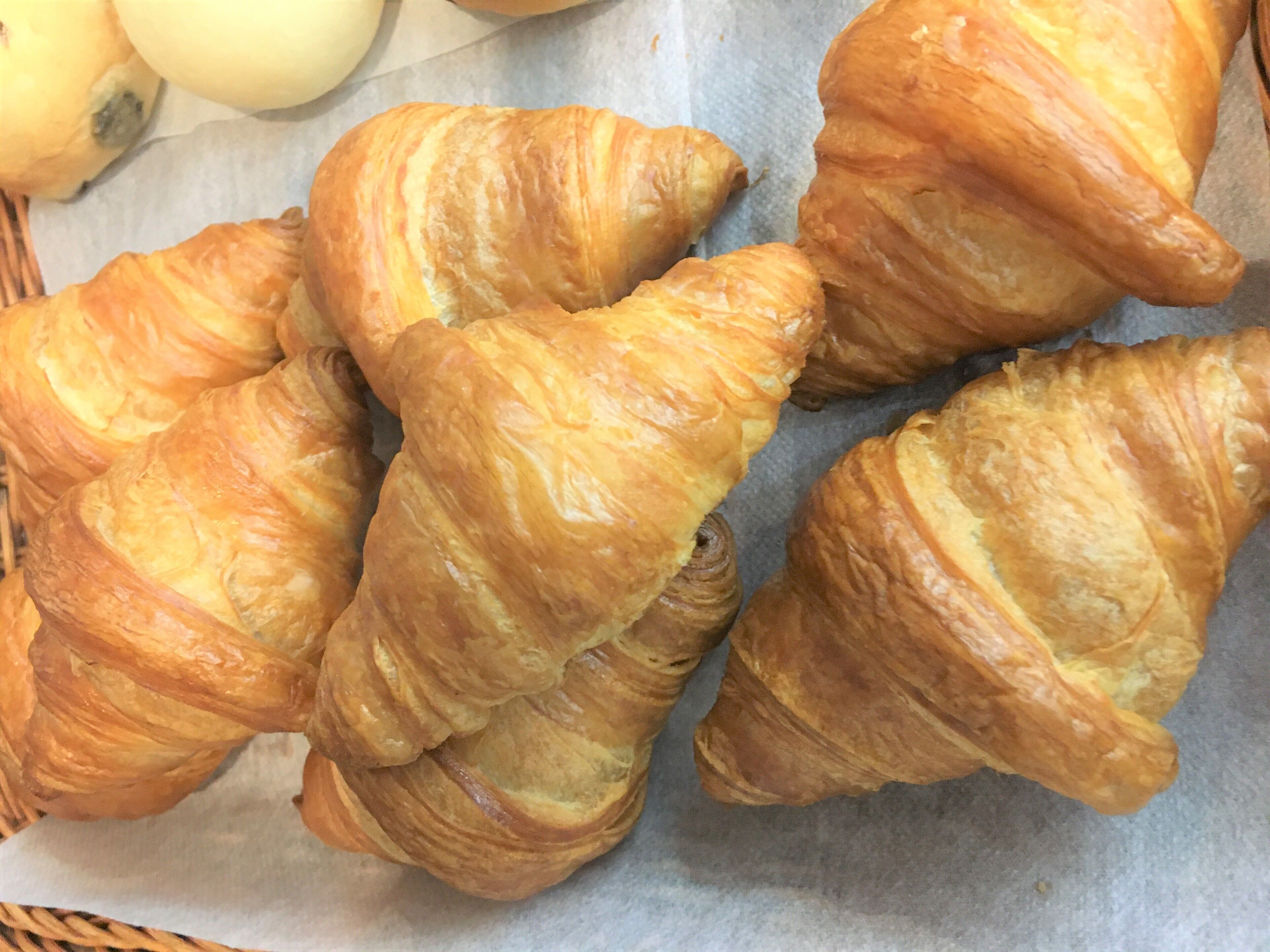 A basket of croissants on a paper-lined tray.