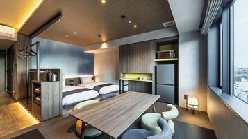 A modern hotel room with a wooden ceiling, two beds, a dining table, and a kitchenette.