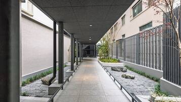 A corridor with a tiled floor, metal railings, and a stone pathway on one side.