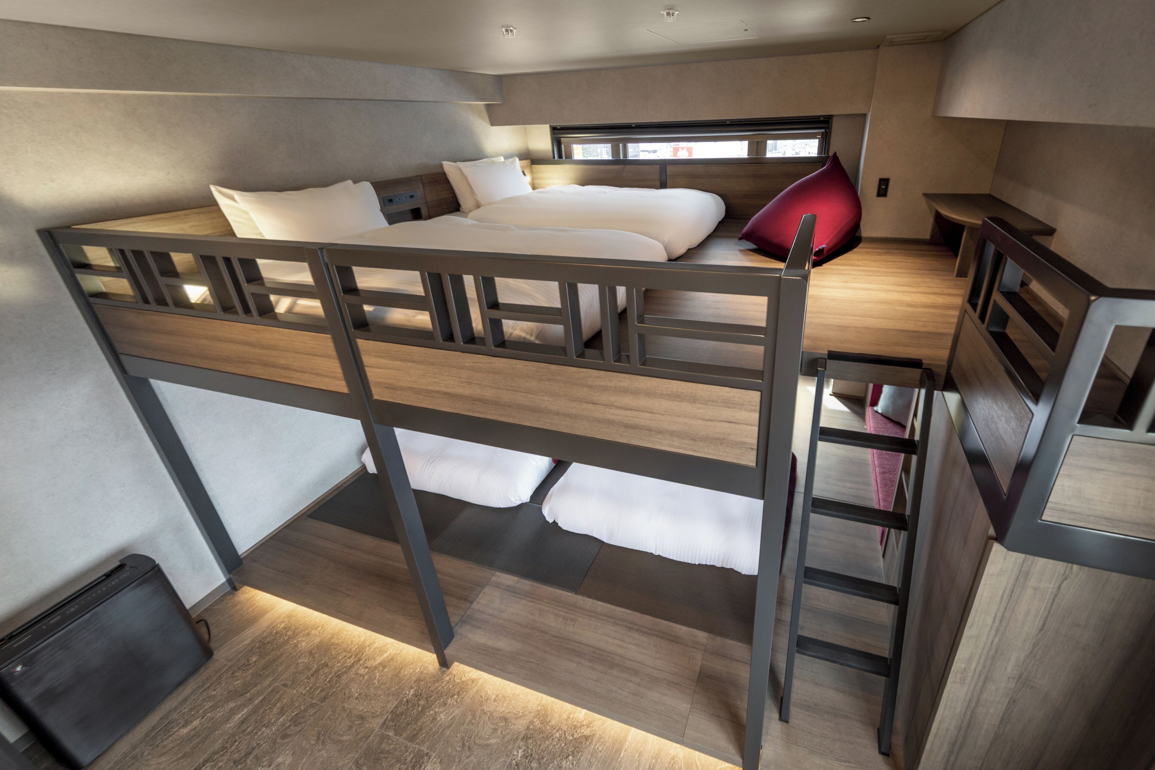 A bunk bed room with a desk and a window.