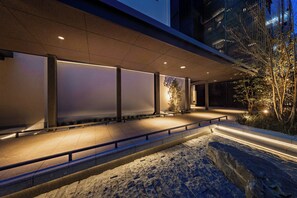 A modern building exterior at night with illuminated panels and a stone pathway. - &Here OSAKA NAMBA (Osaka)