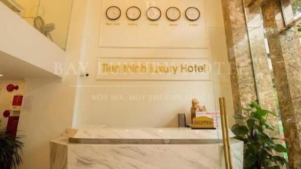 A reception desk with a marble top, a chandelier, and a clock above it. - Tien Thinh Hotel Ha Long- by Bay Luxury (Hong Gai)