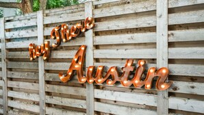 Un recinto in legno con lettere illuminate che compongono la scritta 'Buy There Austin'.