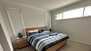 A bedroom with a bed, a nightstand, a lamp, and a window. - Hawks Nest - Magic Square Location (Hawks Nest)