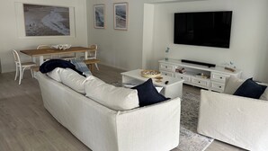 A modern living room with a sofa, coffee table, TV, and artwork on the wall. - Hawks Nest - Magic Square Location (Hawks Nest)