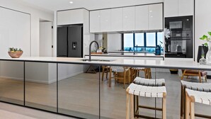 A modern kitchen with white cabinets, a black oven, and a large window offering a view. - Magnoli Apartments  (Palm Beach)