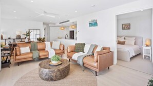 A modern living room with leather sofas, a round coffee table, and a kitchen in the background. - Magnoli Apartments  (Palm Beach)