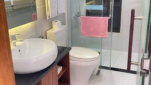Une salle de bain moderne avec une douche à parois de verre, un lavabo blanc et des toilettes.