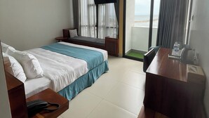 Une chambre d’hôtel équipée d’un lit, d’un bureau, d’une télévision à écran plat et offrant une vue sur l’océan.