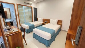 Une chambre d’hôtel avec deux lits, un bureau avec un téléphone, un miroir et un appareil de climatisation.