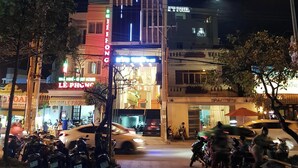 Un immeuble à plusieurs étages, doté d’une enseigne lumineuse, avec les inscriptions « HONG TUYET » et « HÀNH HOTEL » au sommet.